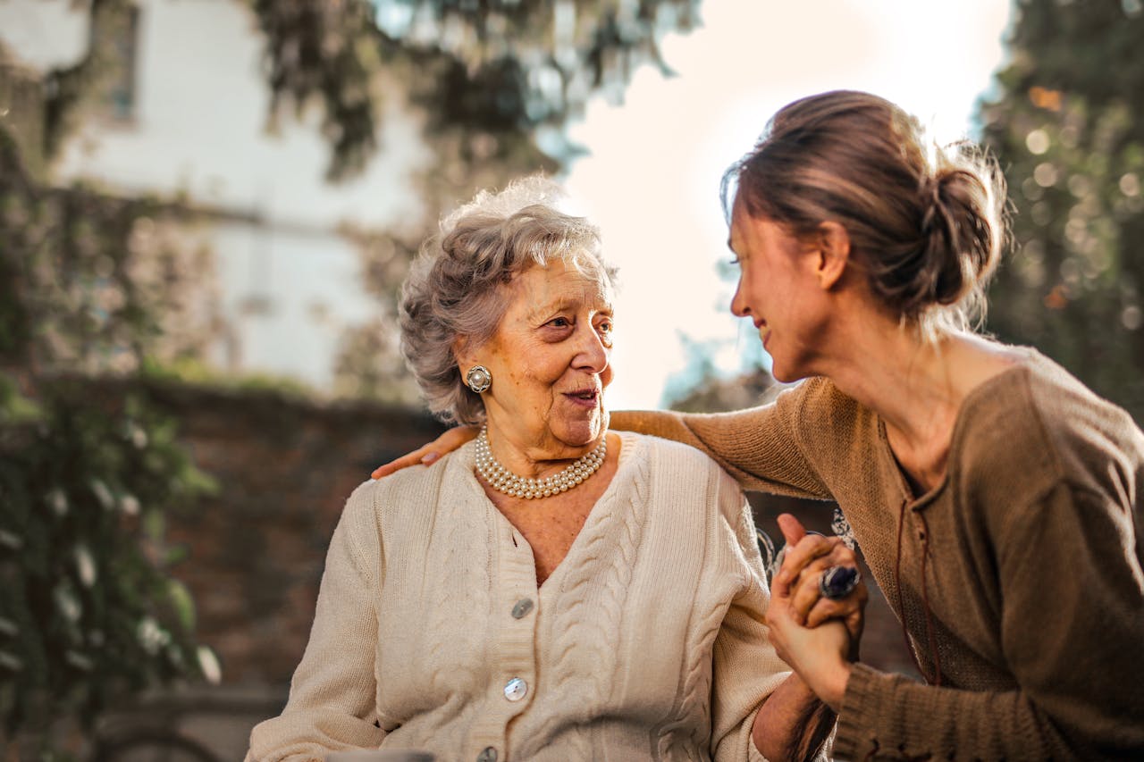 story-01 Elderly woman and adult daughter share a joyful, affectionate moment in a sunny garden.