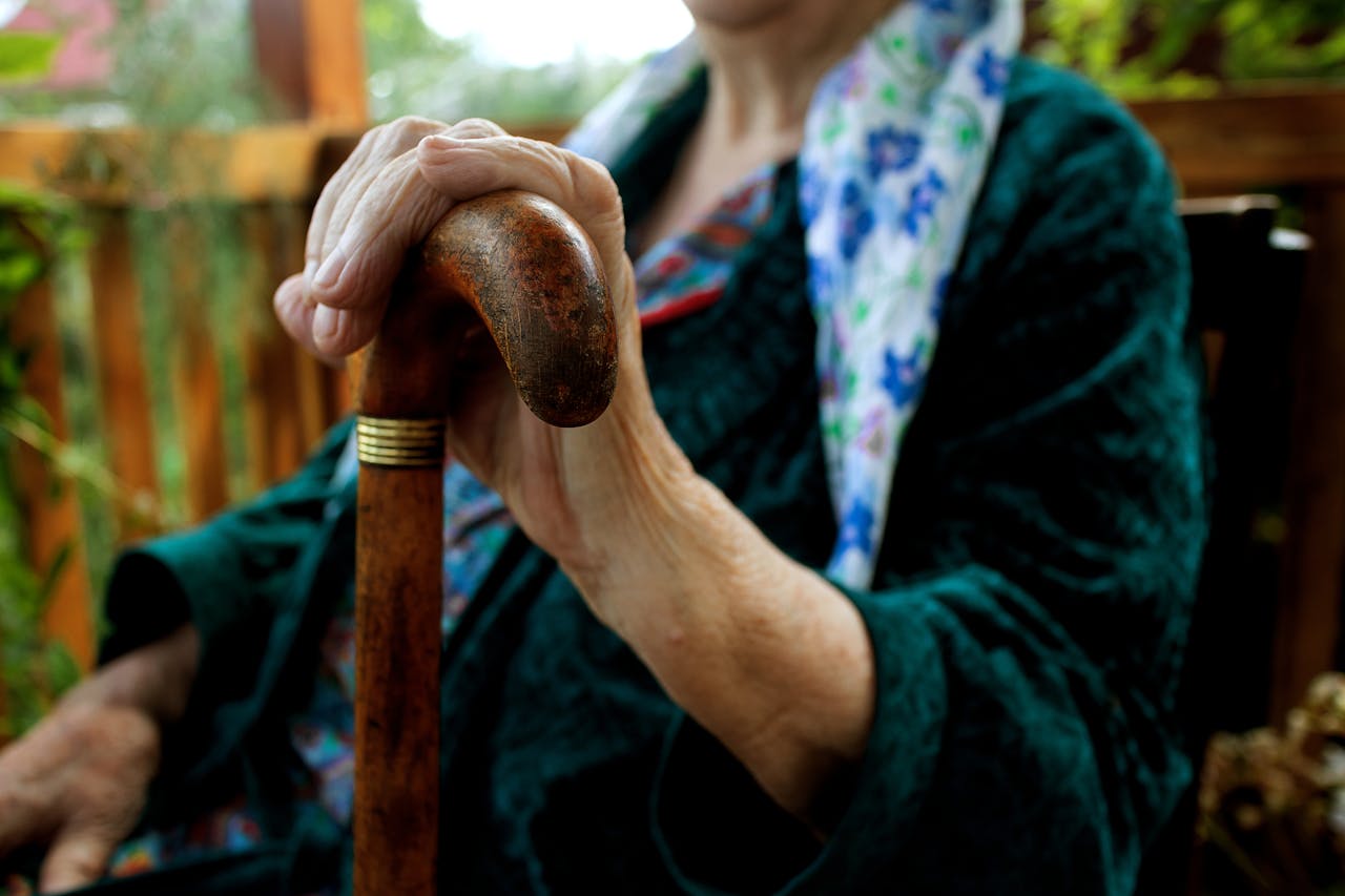 services-04 Senior adult holding a wooden cane, symbolizing strength and support.
